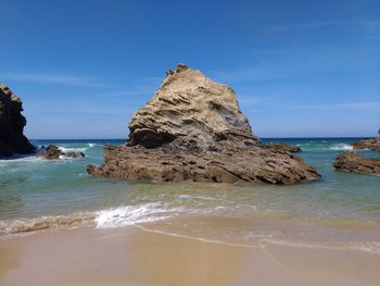 Rock formation on beach against blue sky