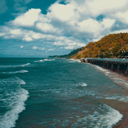 View of calm beach against cloudy sky