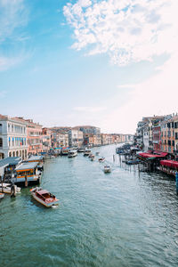 Boats moored in canal by buildings against sky