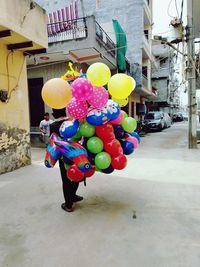 Multi colored balloons at street against building in city