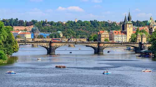 Bridge over river by buildings in city against sky