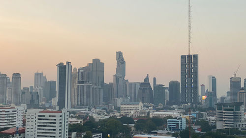 Modern buildings in city against sky during sunset