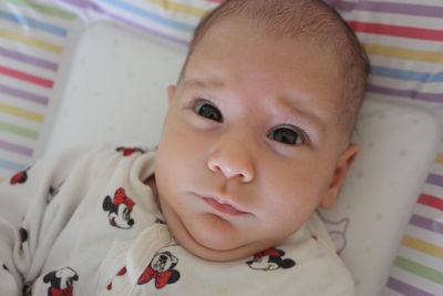 Close-up portrait of cute baby girl on bed at home