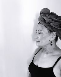 Senior woman with hair wrapped in towel standing against wall at home