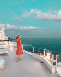 Rear view of woman standing by sea against sky