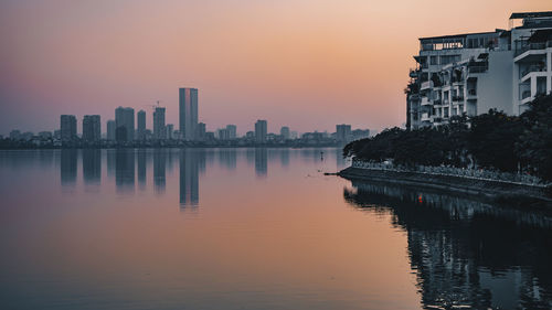 River by buildings against sky during sunset