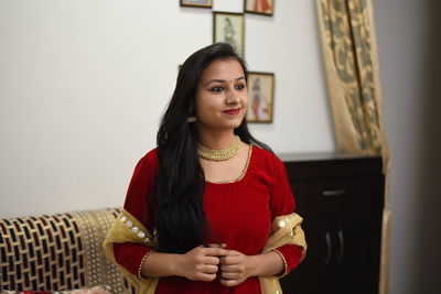 Portrait of a smiling young woman standing at home