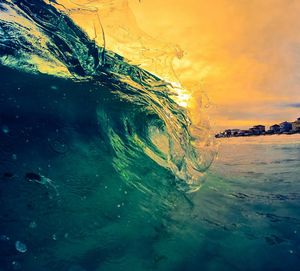 Close-up of sea waves against sky at sunset