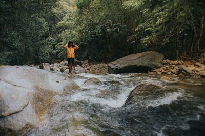 Man standing on rock by river in forest