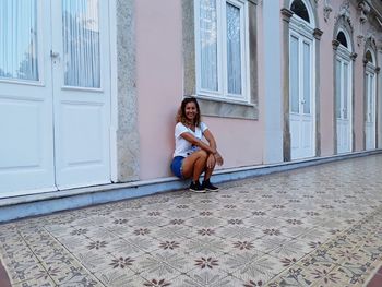 Portrait of smiling young woman sitting against building