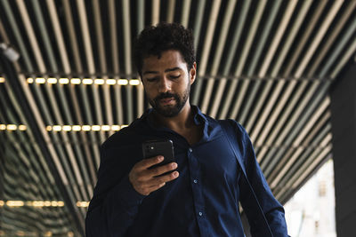 Male business person using smart phone in city