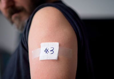 Vaccinated man looking down at plaster bandage on shoulder right after getting covid-19 vaccine shot