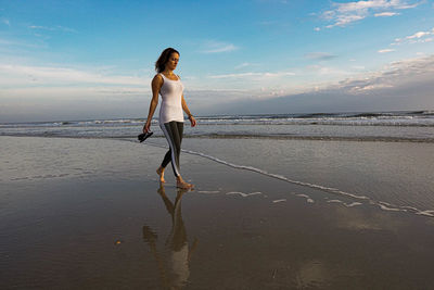 Full length of woman standing on beach against sky