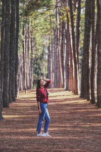 Full length of woman standing amidst trees in forest