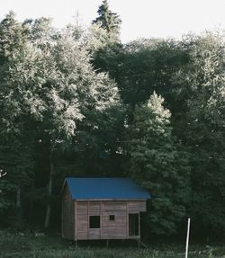 House on field by trees against sky