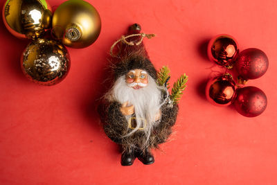 Directly above shot of santa clause with christmas ornament on red background