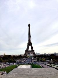 Communications tower in city against cloudy sky