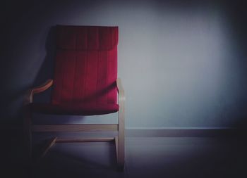 Empty chair by table against wall at home