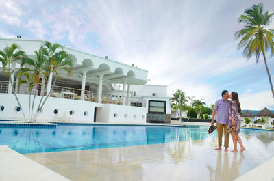 People relaxing in swimming pool against sky