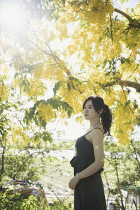 Woman standing by tree against plants