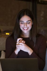 Portrait of young woman sitting on sofa at home