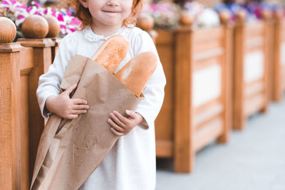 Midsection of smiling girl holding loaf of bread