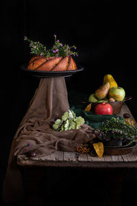 Close-up of fruits in basket on table against black background