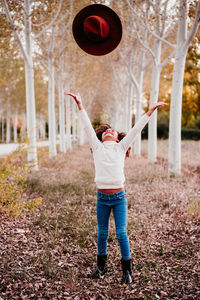 Rear view of boy playing with autumn leaves in background