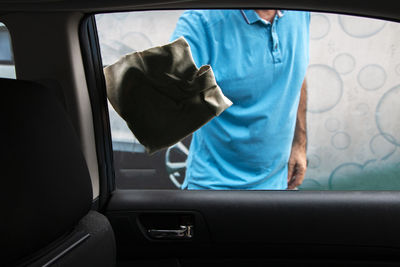 Satisfied mature man polishing his car with microfiber cloth. close-up