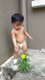 Full length of shirtless boy standing against wall