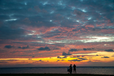 Beautiful scenic view sunset over the ocean horizon with black silhouette of a people