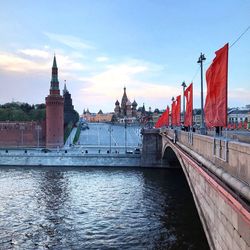 Bridge over river by buildings against sky in city