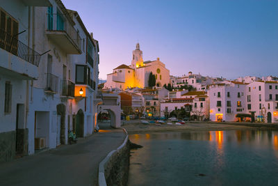 Illuminated buildings in city against clear sky at dusk