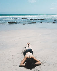 Full length of young woman on beach against sky