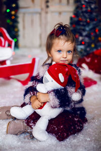 Happy beautiful girl in white dress hugging a teddy bear on the background of the christmas tree