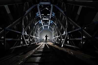 Rear view of silhouette person walking on footbridge