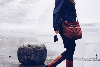 Low section of woman by fountain in city