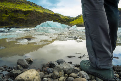 Low section of man standing on rock by lake