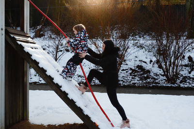 Boy and teenage girl at slide on snow covered playground