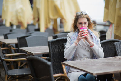 Young woman drinking tea while sitting on table