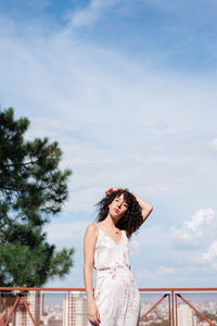 Woman with curly hair standing against sky