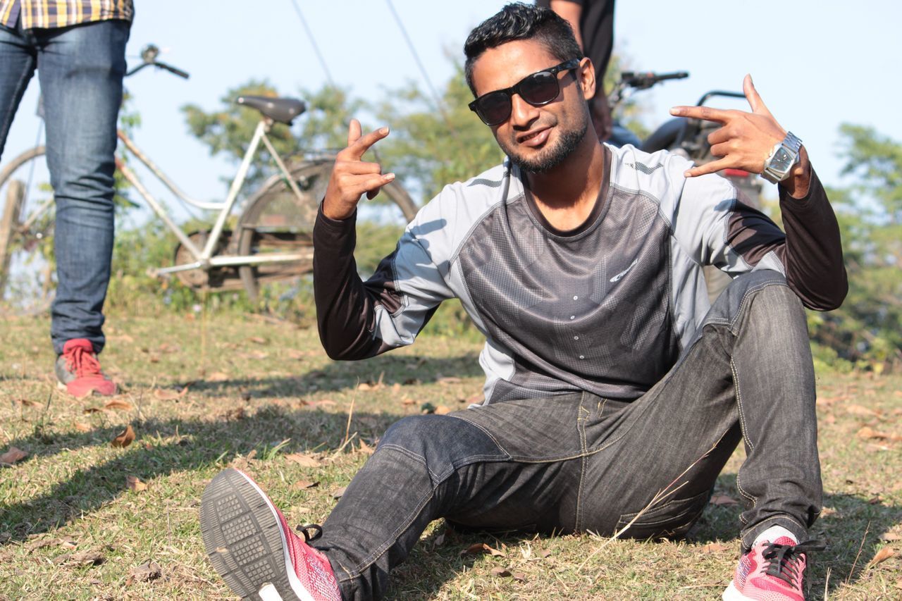 YOUNG MAN SITTING ON FIELD
