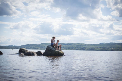 People swimming in lake against sky