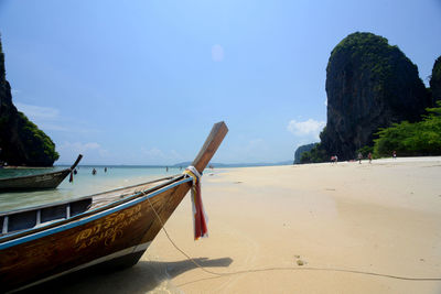 Longtail boats moored at sea shore against sky