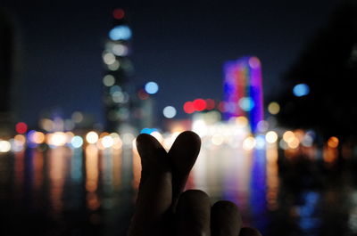 Close-up of hand against illuminated blurred lights