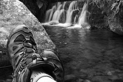 Low section of person standing on rock by river