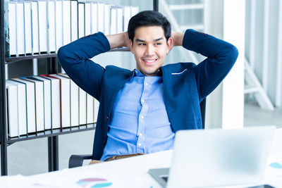 Portrait of young man using laptop at office