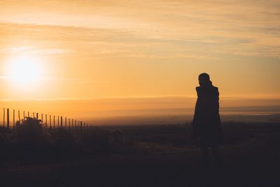 Silhouette man standing against sky during sunset