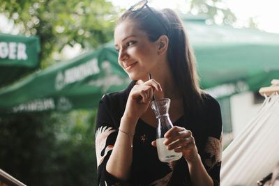 Portrait of a smiling young woman drinking outdoors