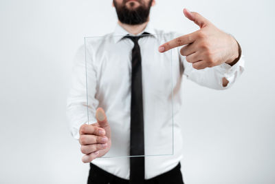 Midsection of businessman with arms crossed standing against white background